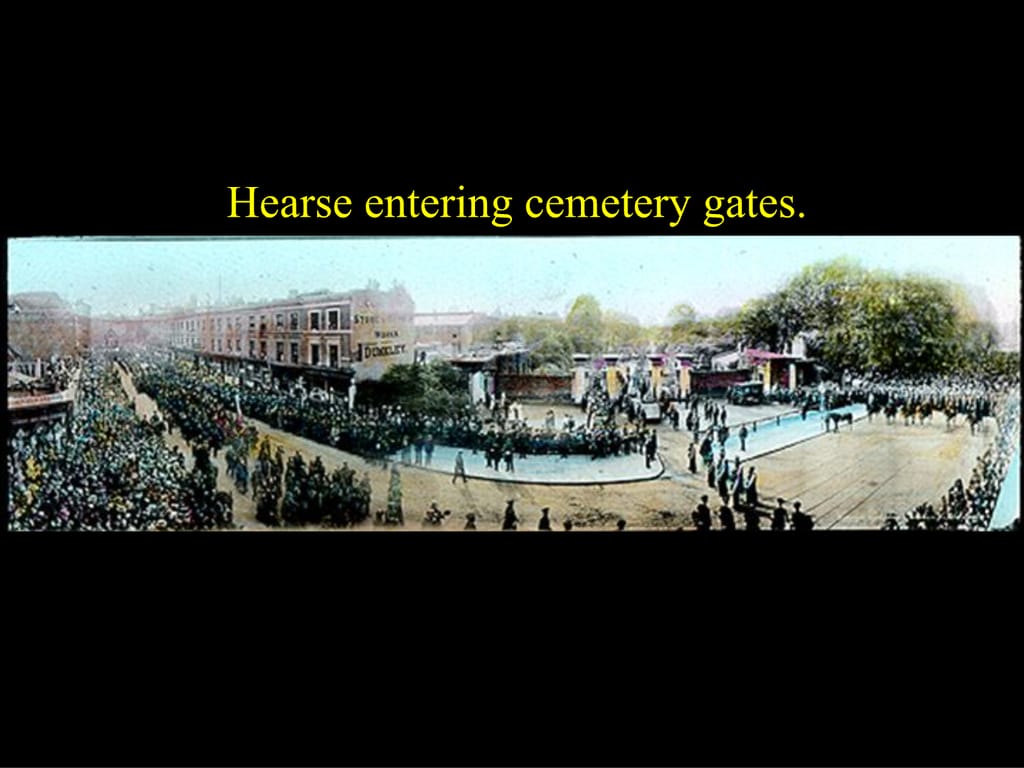 Hearse entering cemetery gates.